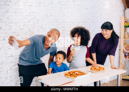 Heureux parents et petit garçon et fille d'un repas et prendre en selfies smartphone à la maison. Famille et parentalité concept Banque D'Images