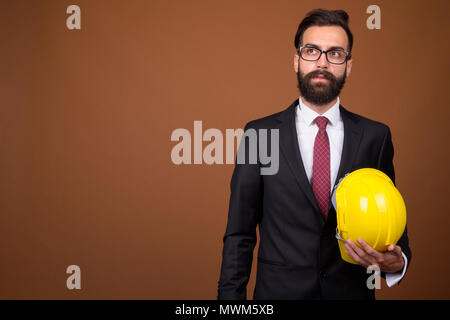Beau jeune homme persan barbu contre brown background Banque D'Images
