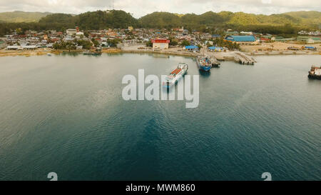 Port de marchandises et de passagers avec des péniches et bateaux de marchandises sur l'île tropicale. Vue aérienne:terminal des ferries passagers Ferries .ville Dapa pour véhicules de transport et les passagers dans le port. Philippines, Siargao. Banque D'Images