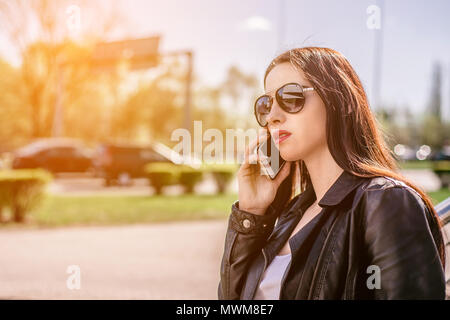 Jolie femme spontanée à parler au téléphone. L'authenticité et de spontanéité. Conversation authentique au téléphone. La fille en lunettes de soleil est tenir Banque D'Images