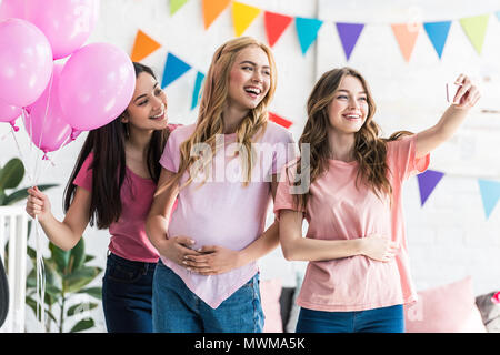 Amis multiculturelle et femme enceinte en tenant avec smartphone selfies à baby-partie Banque D'Images