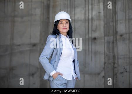 Femme d'âge moyen confiant wearing hard hat looking away Banque D'Images