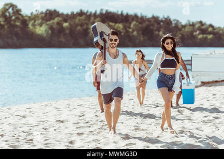 Heureux l'interracial couple holding hands et passer du temps avec leurs amis Banque D'Images