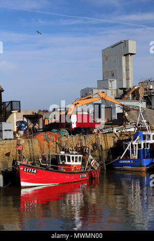 Le rouge et le bleu les bateaux de pêche amarrés au port de Whitstable, Kent, UK, avec l'usine d'asphalte de Brett agrégats dans l'arrière-plan. Banque D'Images