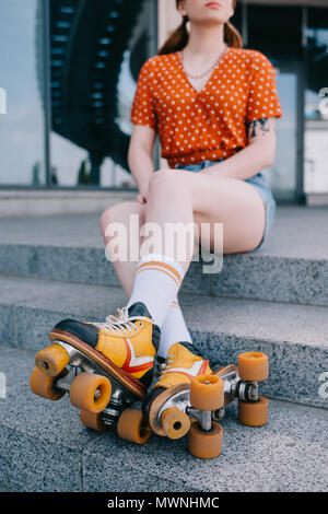 Cropped shot of girl en patins à sitting on stairs Banque D'Images