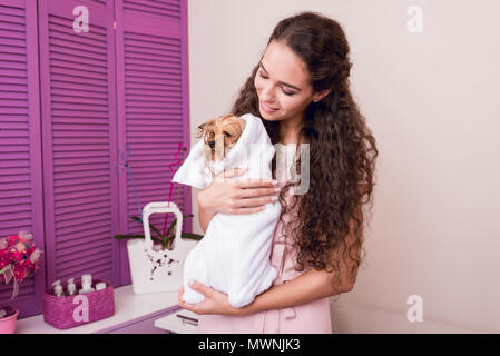 Beautiful smiling woman holding mignon chien yorkshire terrier humide enveloppée d'après bain serviette Banque D'Images