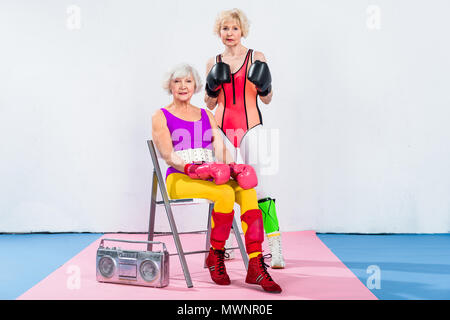 Les femmes âgées sportive dans des gants de boxe looking at camera lors de l'entraînement Banque D'Images