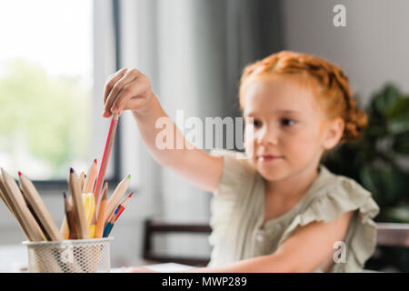 Close-up shot of cute redhead girl choosing color pencil Banque D'Images