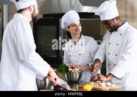 De l'équipe multiraciale des cuisiniers qui travaillent ensemble dans une cuisine de restaurant Banque D'Images