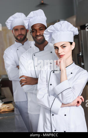 Équipe de cuisiniers multiraciales portant uniforme blanc dans une cuisine de restaurant Banque D'Images