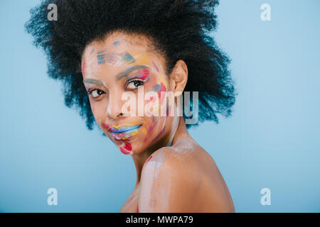 Jeune femme avec des traits de peinture sur visage isolé sur blue Banque D'Images