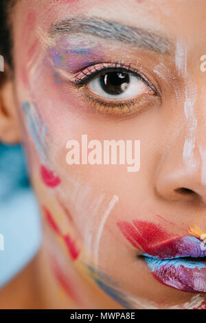 Cropped shot de jeune femme avec des traits de couleur sur le visage à la caméra à sur bleu Banque D'Images