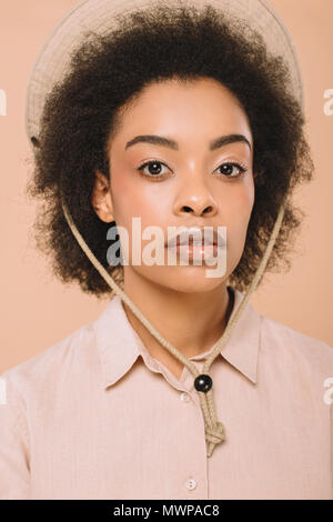 Belle jeune femme dans l'élégant quartier de hat et shirt looking at camera isolé sur beige Banque D'Images