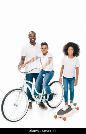 Happy african american father avec mignon enfants équitation location et skateboard isolated on white Banque D'Images