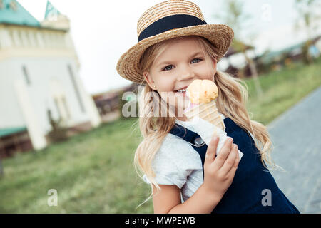 Portrait of smiling little girl avec de la crème glacée dans la main looking at camera Banque D'Images