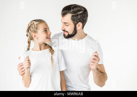 Happy father and daughter holding des brosses à dents et sourire chaque autres isolated on white Banque D'Images