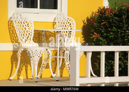 Photo de tableau blanc et d'une chaise en face de maison jaune Banque D'Images