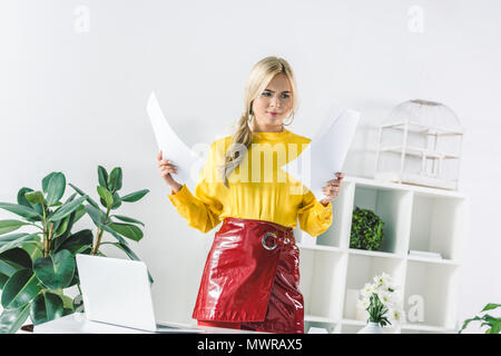 Cheerful businesswoman holding documents in modern office Banque D'Images