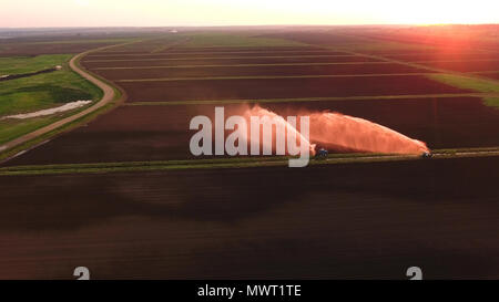 Équipement d'Irrigation Arrosage Irrigation fraîchement ensemencée domaine.au coucher du soleil.L'irrigation de terres agricoles pour assurer la qualité de la récolte. Vue aérienne:système d'irrigation d'arroser un champ agricole. Banque D'Images