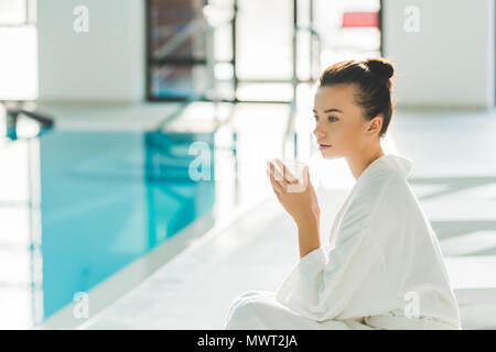 Young woman in bathrobe avec tasse de café à spa Banque D'Images