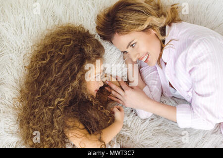 Vue de dessus de la mère et de l'heureux curly adorable fille couchée sur couverture en peau de mouton Banque D'Images