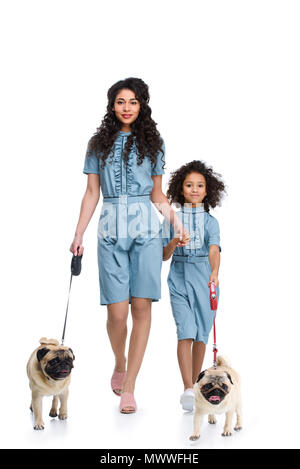 Belle Mère et fille en robes semblables à marcher avec le carlin isolated on white Banque D'Images