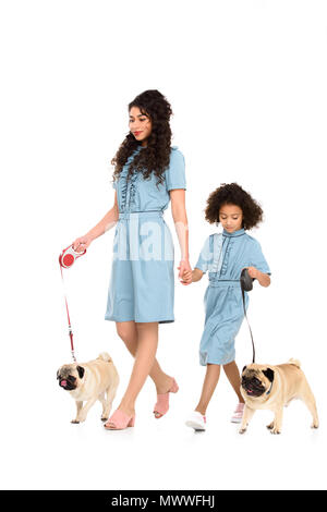 Jeune mère et fille en robes semblables à marcher avec le carlin isolated on white Banque D'Images