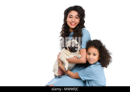 Mère et fille embrassant adorable carlin isolated on white Banque D'Images