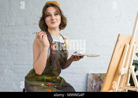 Jeune fille d'inspiration travailler avec la peinture de chevalet par couteau dans le Light Studio Banque D'Images