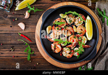 Crevettes Crevettes au beurre à l'ail rôti avec du citron et du persil sur fond de bois. Alimentation saine. Vue d'en haut. Mise à plat. Banque D'Images