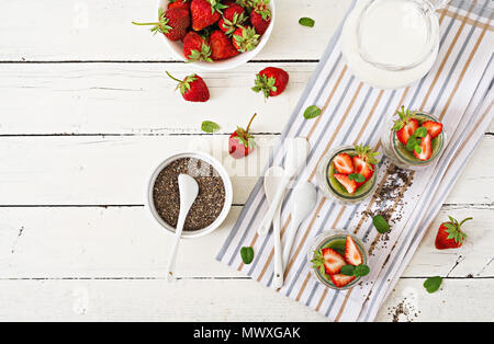 Detox et de l'air sain petit déjeuner en pot. Lait de coco vegan chia seeds au lait avec des fraises et des kiwis. Vue d'en haut. Mise à plat. Banque D'Images