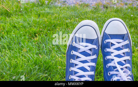 Les jeunes sneakers, chaussures sur l'herbe verte durant les journées ensoleillées d'été sereine, jour bleu classique sneakers sur l'herbe verte dans le jardin. Banque D'Images