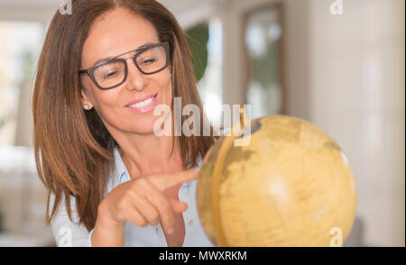 L'âge moyen woman pointing at world globe. Elle est le choix prochain pays de voyager Banque D'Images