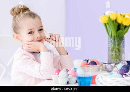 Petit enfant jouant avec statuette de lapin de Pâques et oeufs peints Banque D'Images