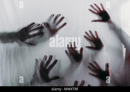 Silhouettes floues effrayant de mains humaines touchant le verre dépoli Banque D'Images