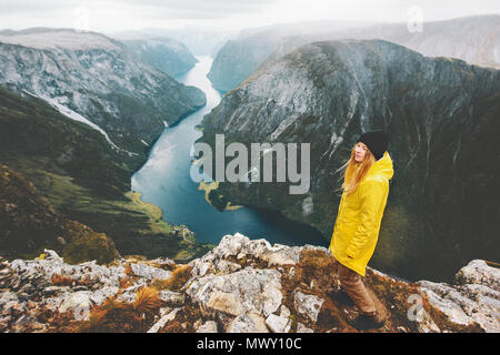 Woman traveler sur falaise montagne voyager seul vacances d'aventure de vie en Norvège fjord aérienne voir girl wearing imperméable jaune walki Banque D'Images