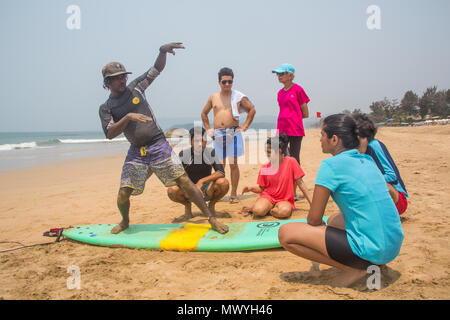 Velu, fondateur de Aloha Surf Inde, montrant comment certains élèves de se tenir debout sur une planche de surf sur la plage d'Agonda. Banque D'Images