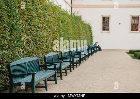 Un grand nombre d'enclos dans une rangée de bancs. Sur le dernier banc, un couple d'amoureux ou d'amis rencontrés et communiquer, les gens sont floues Banque D'Images