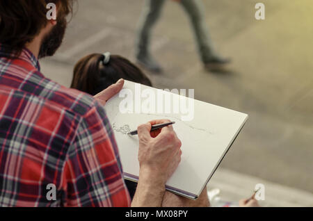 Man painting un paysage sur un morceau de papier assis dans la rue. L'homme artiste peinture à la main photo sur papier. Banque D'Images