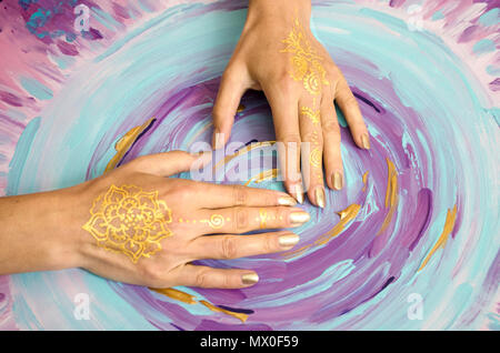 Deux mains paumes Mehndi vide bas isolé sur fond peint. Modèle d'or. L'art-thérapie. Banque D'Images