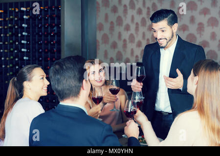 Jeune homme barbu prononcer des toasts sur réunion amicale en agréable restaurant Banque D'Images