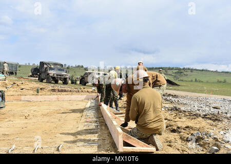 1ère classe constructeur français Jonathan et Builder 3 classe de la Marine Samantha Kylberg Bataillon de construction Mobile 1 Travailler avec les soldats de la 10e Brigade Ingénieur roumain de la construction d'un bâtiment de stockage et d'opérations dans le cadre de Resolute Château 17 au Centre national de formation conjointe, Cincu, Roumanie. Les Seabees ont terminé la fondation et sont la mise en forme pour le béton. Château ferme 17 est un exercice le renforcement de l'alliance de l'OTAN et de renforcer sa capacité de formation conjointe et de réponse aux menaces dans la région. Banque D'Images