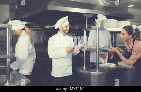Personnel du restaurant avec jeune chef cuisinier travaillant ensemble dans la cuisine Banque D'Images