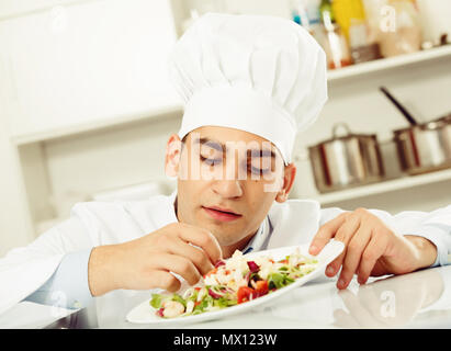 Mâle est degustating sur salade de cuisine. Banque D'Images