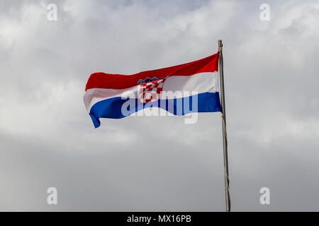 Le drapeau croate voler contre un ciel couvert, nuageux contexte au cours de la vieille ville de Dubrovnik, Croatie. Banque D'Images