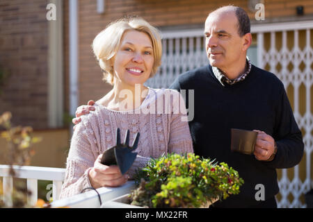 Heureux de parler avec femme mature homme voisin au balcon Banque D'Images