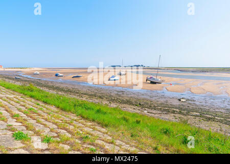 Du haut d'une banque d'herbe en pente à travers l'estuaire à marée basse, où les petits yachts et bateaux à moteur s'asseoir sur le sable, à travers les marais salants Banque D'Images