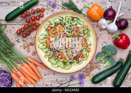 Salade de légumes renforts spiralés dans une cuvette entourée de légumes sur bois Banque D'Images