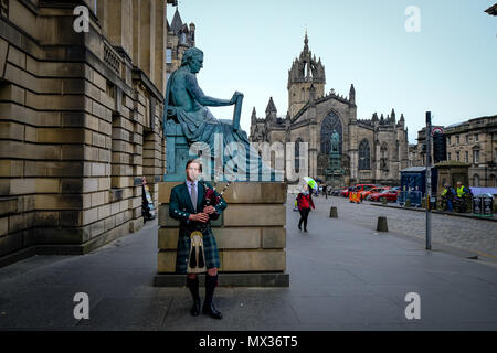 Édimbourg, Écosse - 27 Avril 2017 : joueur de cornemuse écossaise traditionnelle avec peignoirs highlander jouant sur le Royal Mile, avec la cathédrale St Giles dans l'arrière-plan Banque D'Images