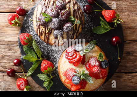 Belles galettes de fruits avec du chocolat, menthe, fraises, cerises et bleuets close-up sur la table. Haut horizontale Vue de dessus Banque D'Images